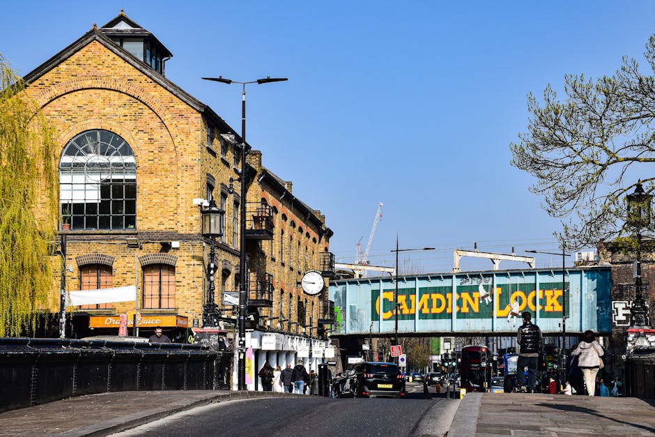 The image depicts a busy street scene in Battersea, with a row of multi-storey brick residential buildings featuring pitched roofs and large windows visible on the right side of the image. In the fore